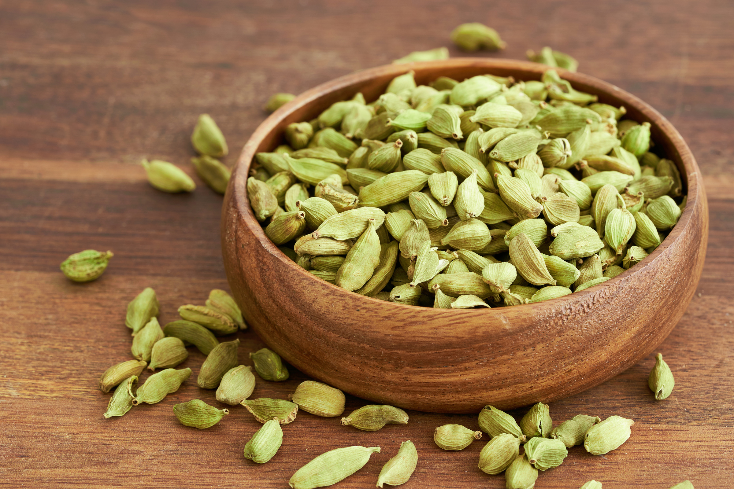 pile of green cardamom cardamon  in wood plate on table background. green cardamom cardamon. heap of green cardamom cardamon food background